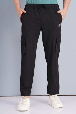 Person wearing black cargo pants with a plain background