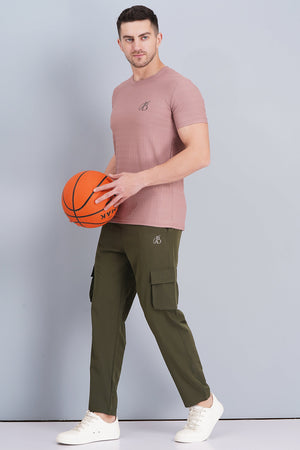 Man holding a basketball wearing a pink t-shirt and green cargo pants on a gray background