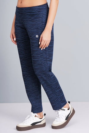 Person wearing navy patterned pants and white sneakers with black accents on a gray background