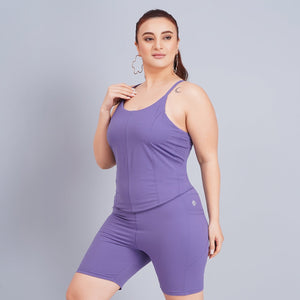 Woman wearing a purple athletic outfit with white sneakers on a gray background