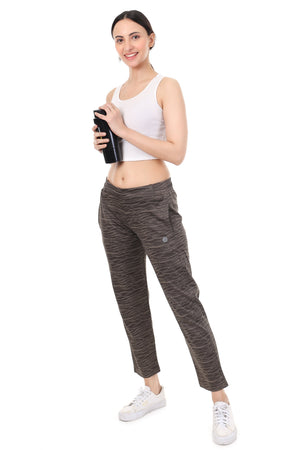 Woman wearing a white sports bra and brown leggings holding a black water bottle on a white background