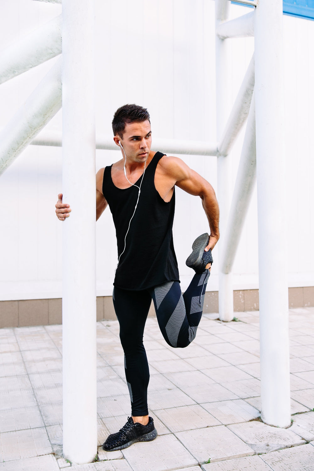 Man stretching outdoors near white metal structures
