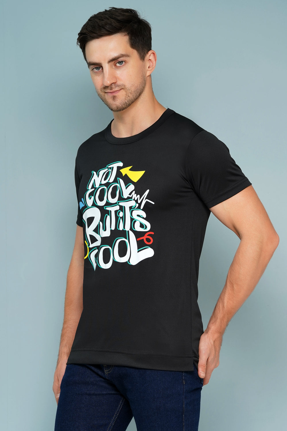Man wearing a black t-shirt with colorful text design against a light blue background