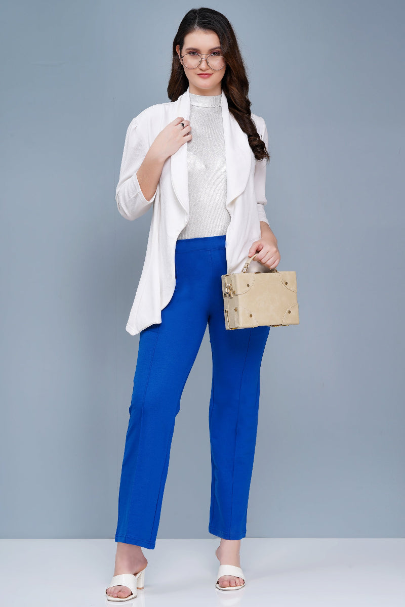 Woman wearing a white top, blue pants, and a white jacket holding a wooden box against a gray background