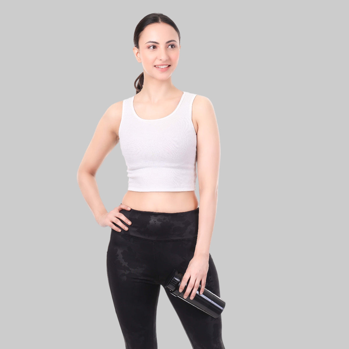 Woman wearing a white tank top and black leggings on a white background