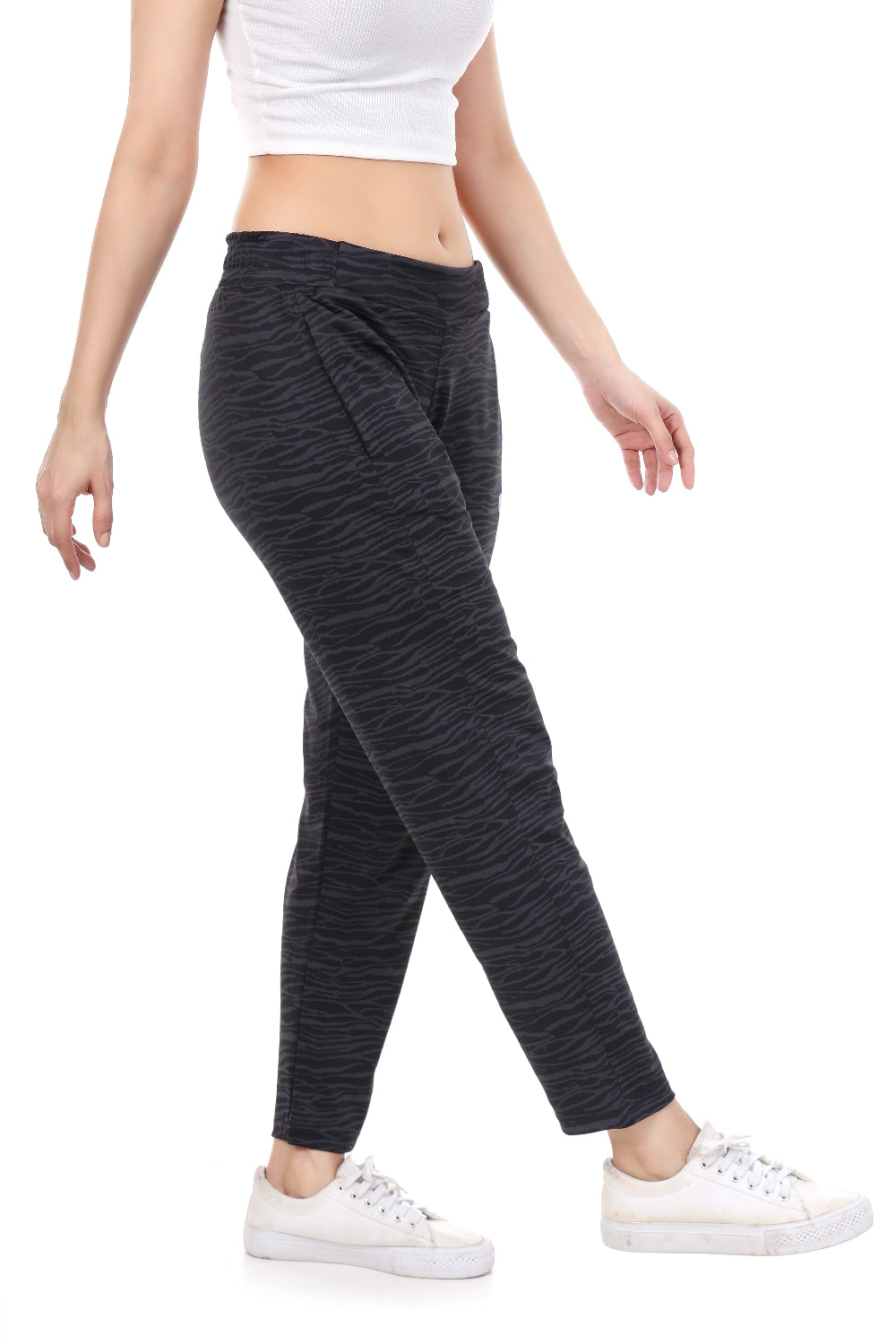 Person wearing dark gray jogger pants and white sneakers on a white background